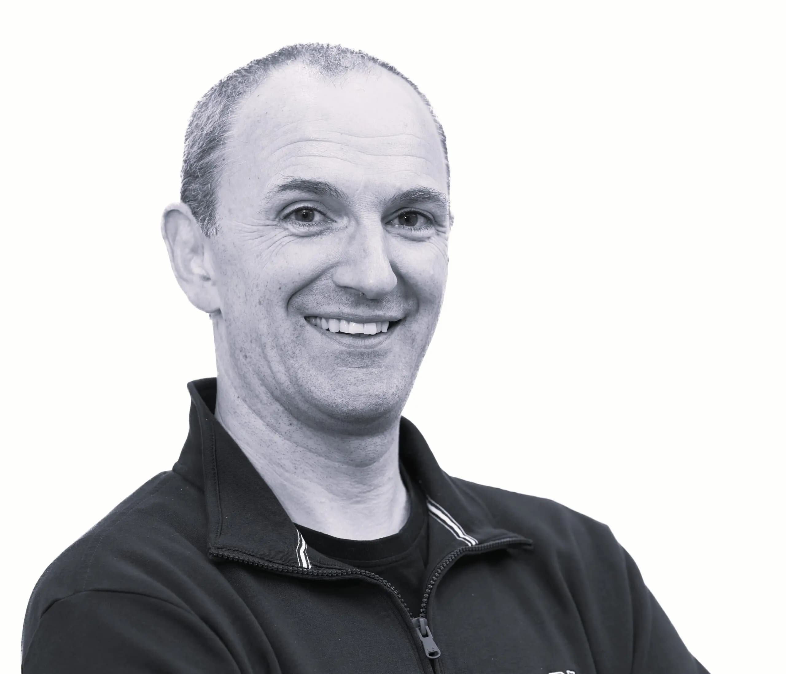 Black and white photo of JJ Cahill smiling, our Chief Financial Officer.
