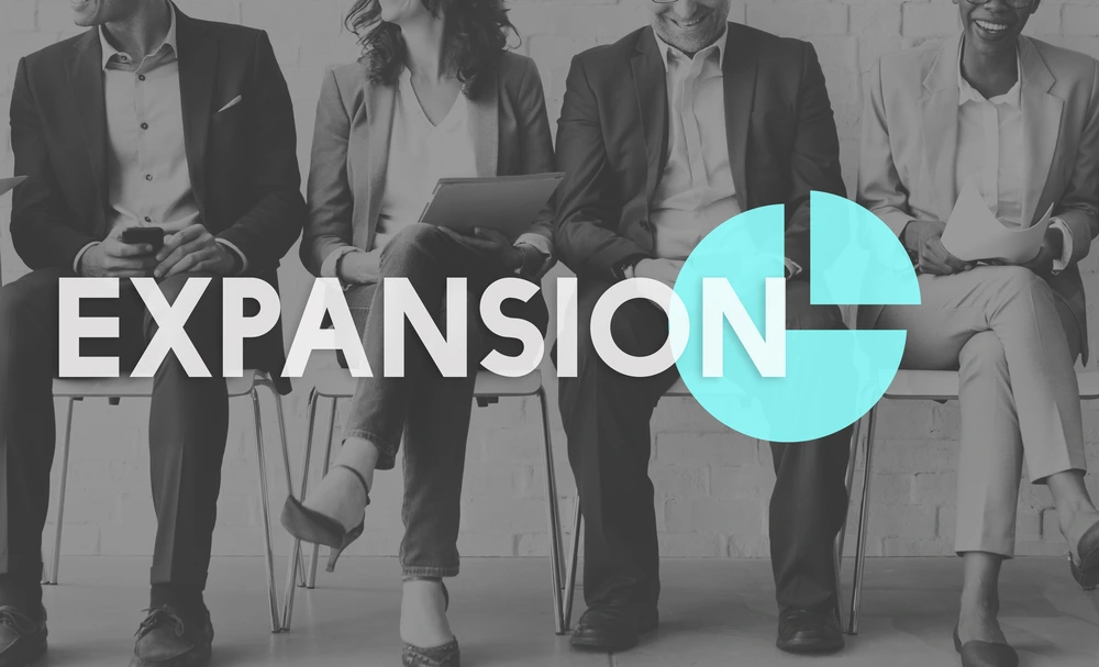 the word expansion layered over a photo of four businesspersons sitting in chairs