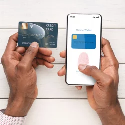 closeup of a man holding a credit card in his left hand and entering the information into his digital wallet on his mobile phone in his right hand