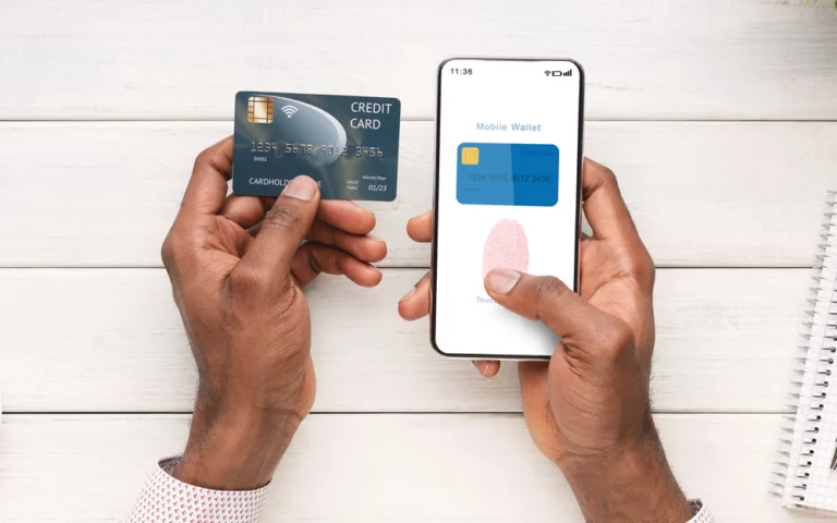 closeup of a man holding a credit card in his left hand and entering the information into his digital wallet on his mobile phone in his right hand