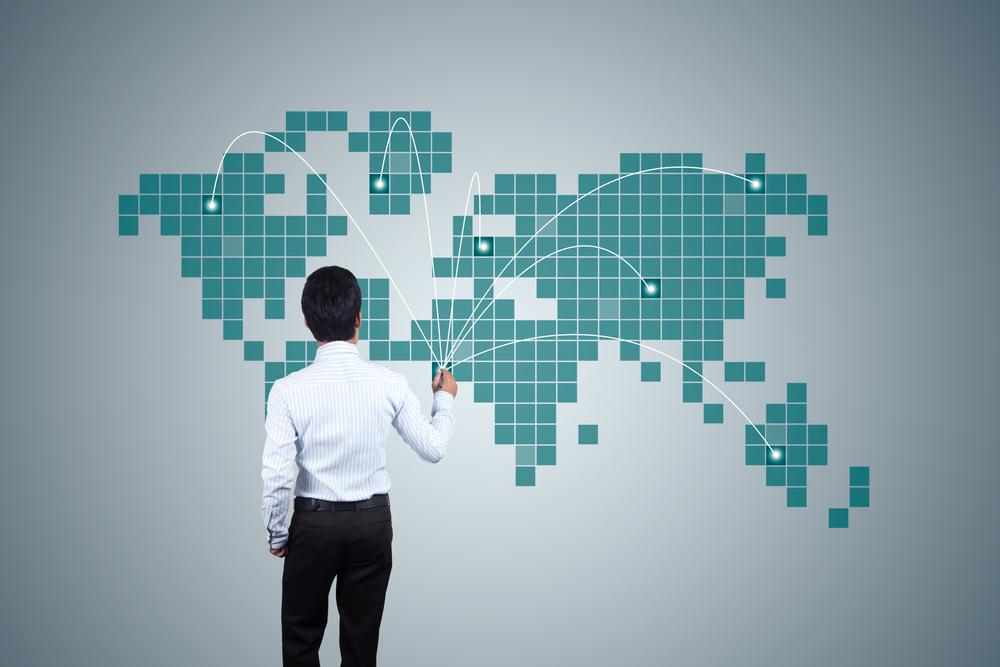 a business man stands in front of a pixelated map illustrating scaling enterprise ecommerce