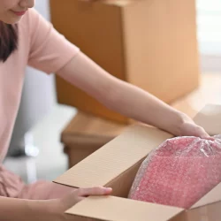 Close up of a woman opening a box containing a pink shirt