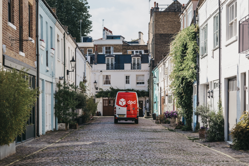 A DPD last-mile delivery van drives down a cobblestone street