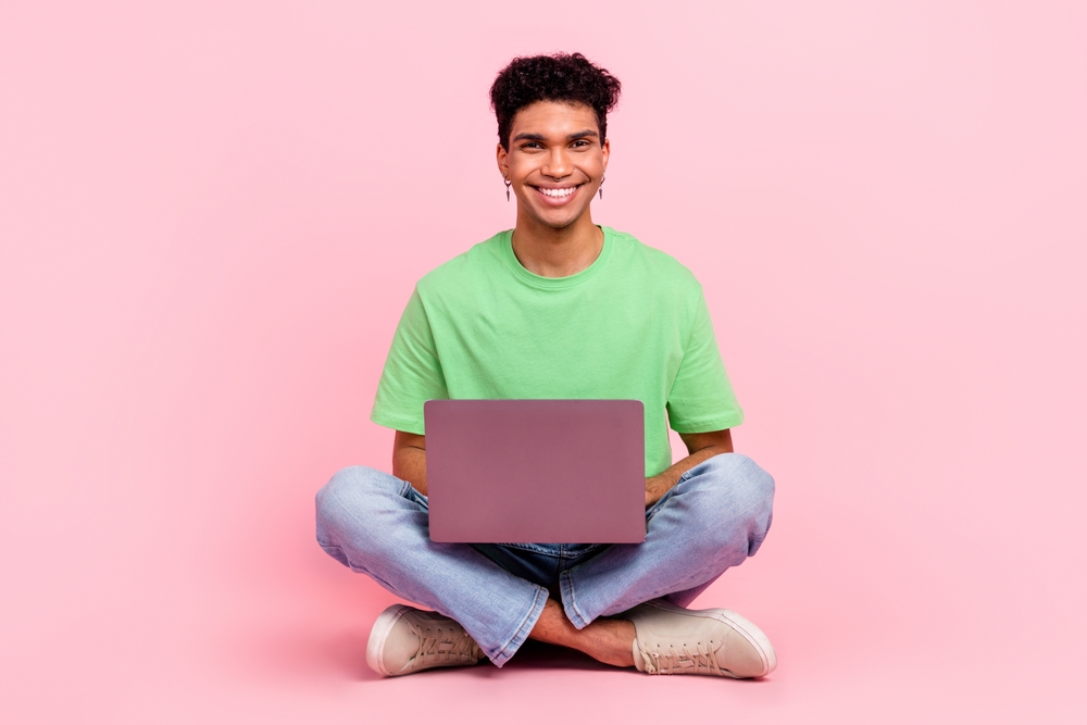 a young male consumer is holding a laptop and smiling