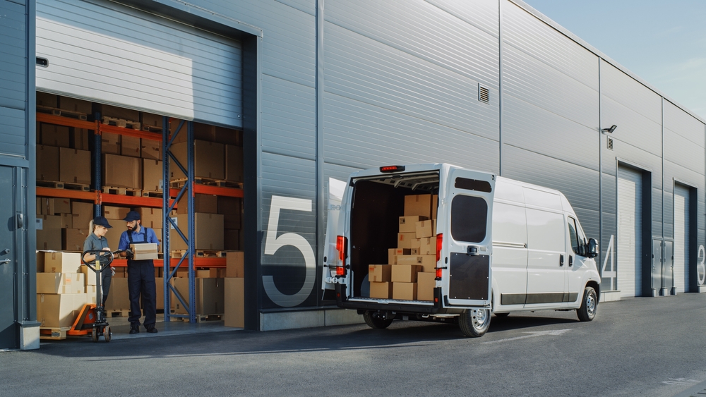 A last-mile delivery van sits outside a warehouse