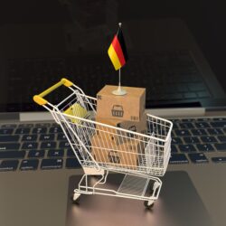 a miniature shopping cart with the German flag sits on a laptop's touchpad