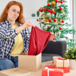a woman looks at a christmas sweater, doesn't like it and wants to return it